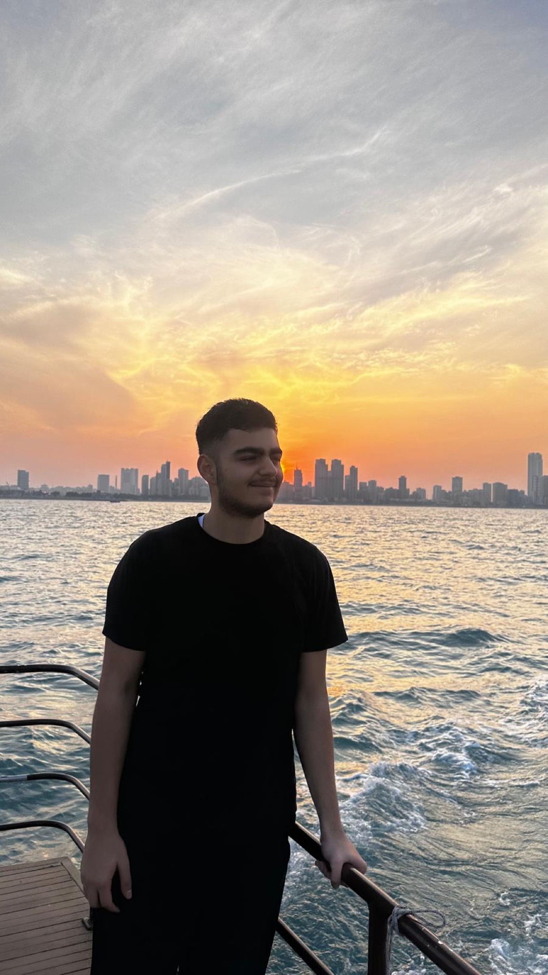 Tarek Tahhan at the waterfront with the Kuwait City skyline behind him at sunset