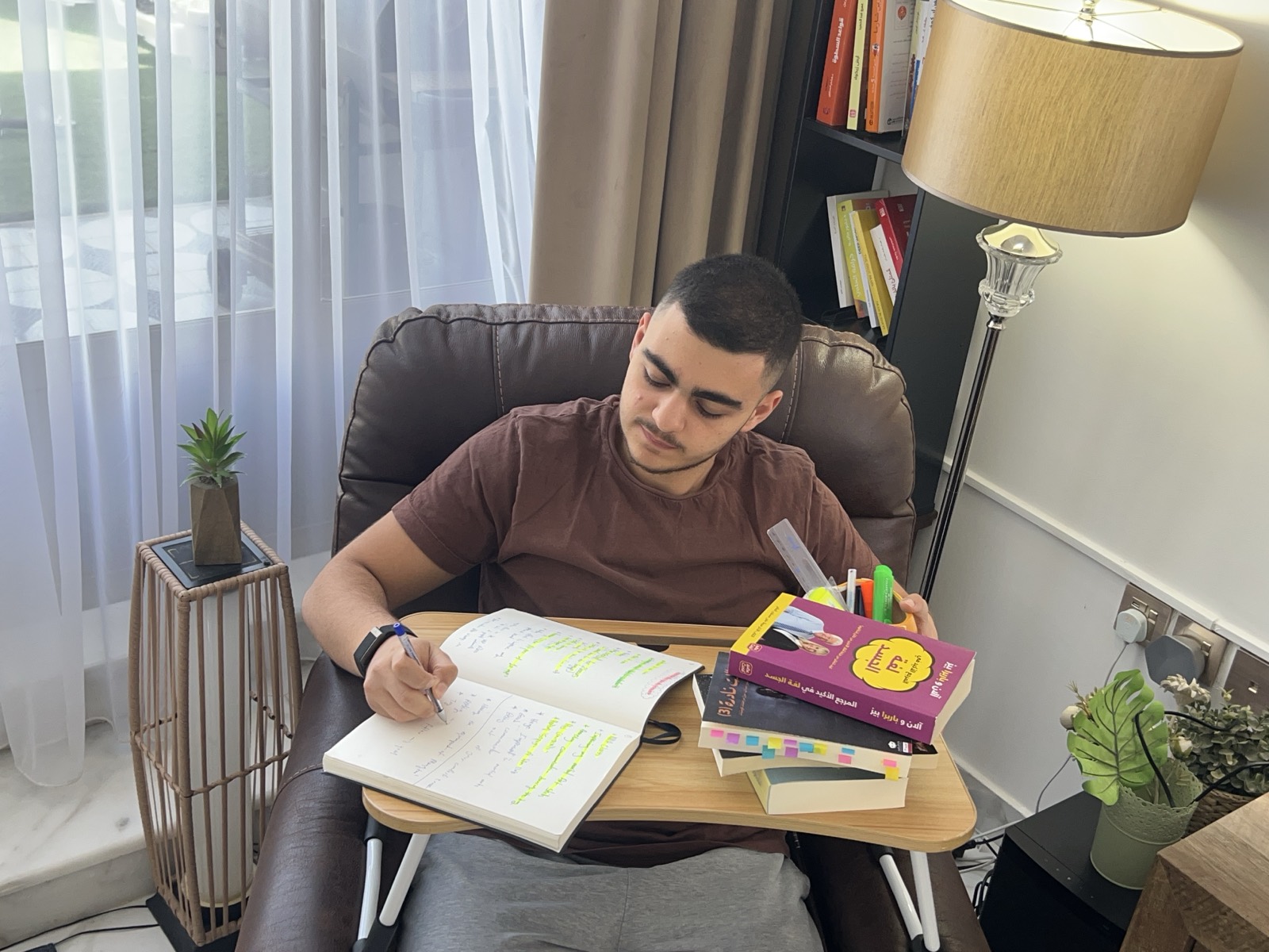 Tarek Tahhan studying at home with an open notebook of handwritten notes and a stack of books